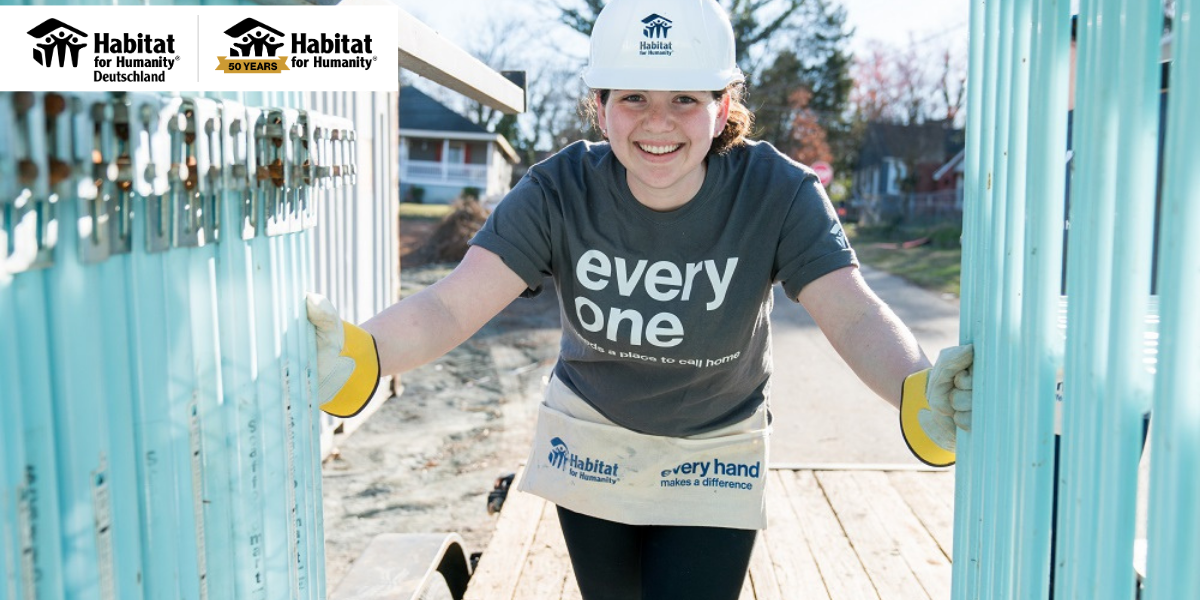 50 Jahre Habitat for Humanity | Headerbild mit junger Frau auf Baustelle mit weißem Bauhelm, die in die Kamera schaut
